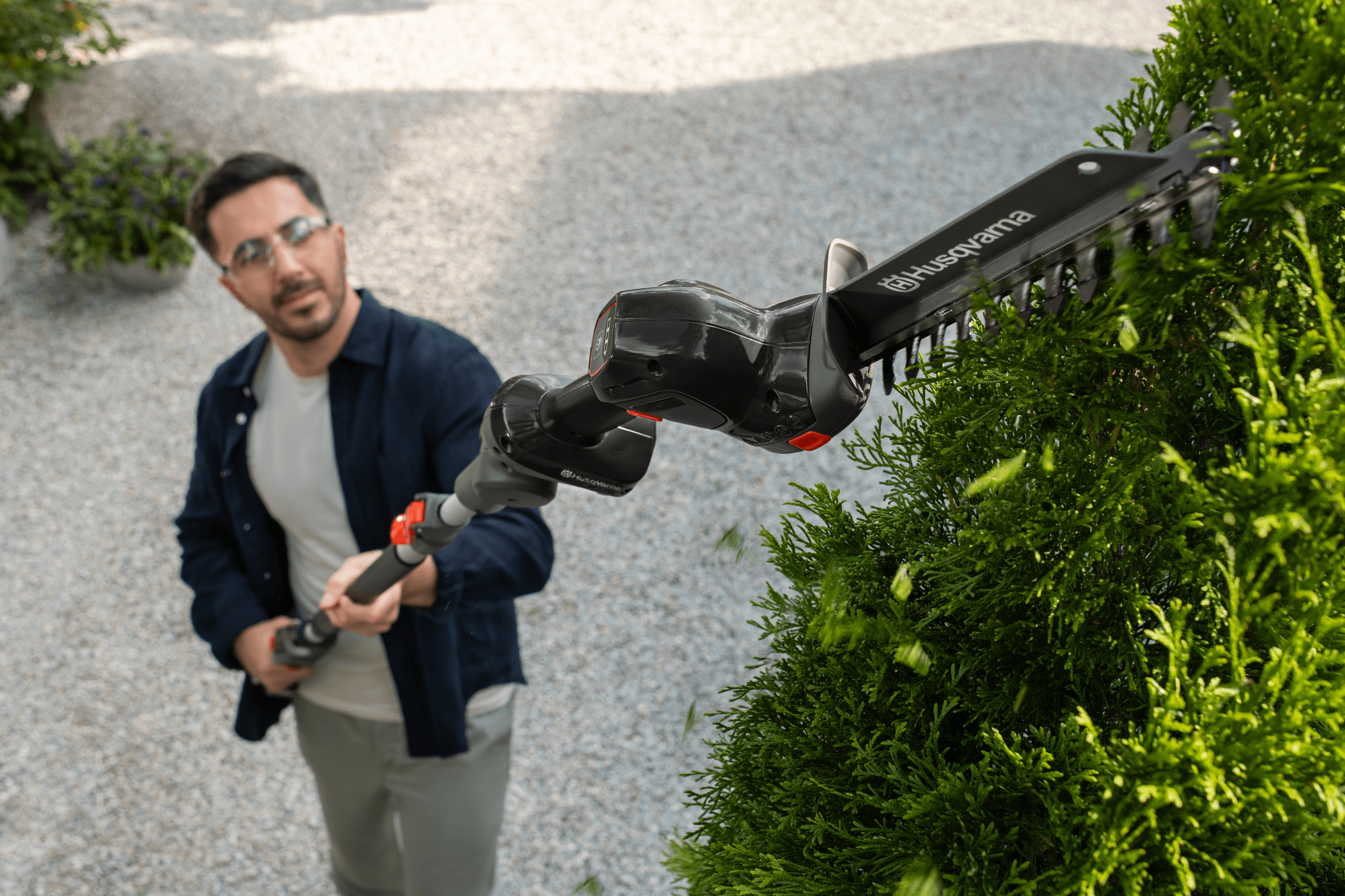 man holding polesaw whilst cutting tree